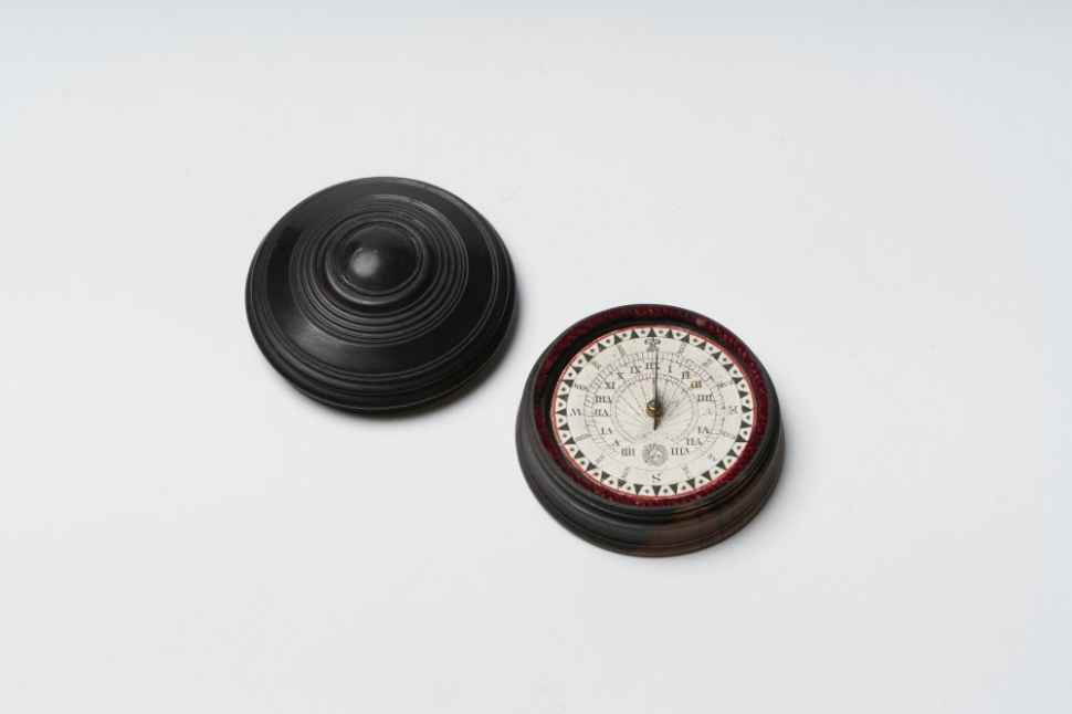 Wooden compass pointing North accompanied by a round wooden lid.