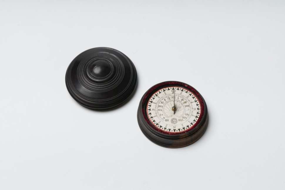 Wooden compass pointing North accompanied by a round wooden lid.
